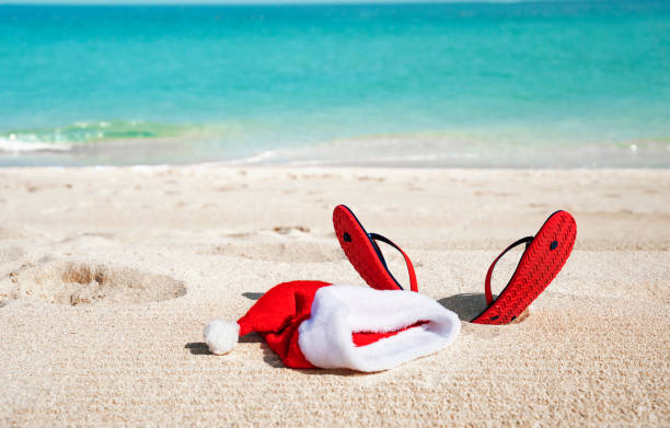 Christmas holidays in hot countries concept. Christmas hat and sandals of Santa Claus on sandy tropical ocean beach - Christmas hat and sandals of Santa Claus on sandy tropical ocean beach - Christmas holidays in hot countries concept arabian sunglasses stock pictures, royalty-free photos & images