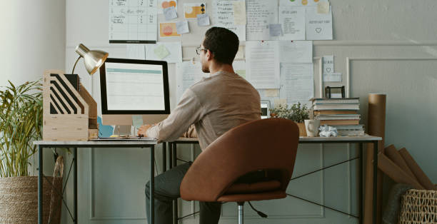 istock Shot of an unrecognisable businessman sitting alone and using his computer while working from home 1357880800