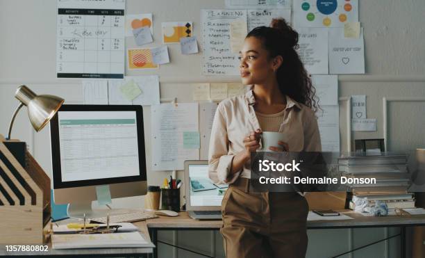 Shot Of An Attractive Young Businesswoman Standing And Looking Contemplative While Holding A Cup Of Coffee In Her Home Office Stock Photo - Download Image Now