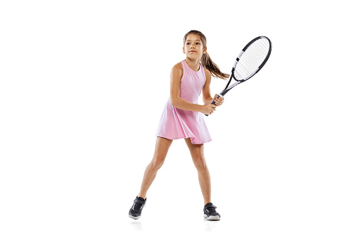 Training before tennis tournament. Sportive little girl, kid, beginner tennis player practicing isolated on white background. Active lifestyle, sport, study, childhood concept. Copy space for ad