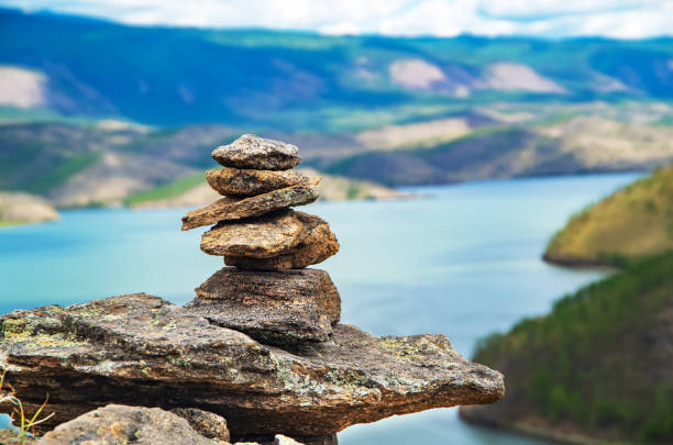 zen concept. a pyramid made of stone on top of a mountain against the backdrop of lake baikal. stone pyramid for meditation. harmony and meditation. zen stones. - aspirations pebble balance stack imagens e fotografias de stock