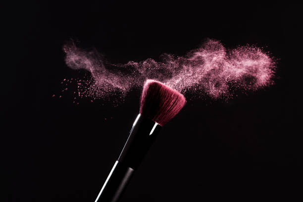 분홍색 파우더가 달린 메이크업 브러쉬는 검은 색 배경에 폭발적인 폭발을 일으킵니다. 뷰티 컨셉. 화장품 배경. - make up brush face powder make up isolated 뉴스 사진 이미지