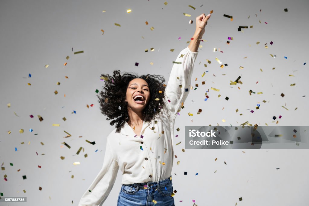 Beautiful excited woman at celebration party with falling confetti Joyful laughing woman celebrating Birthday or New Year eve, having fun, enjoying life concept Celebration Stock Photo