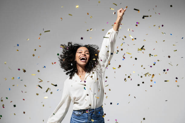 Beautiful excited woman at celebration party with falling confetti stock photo