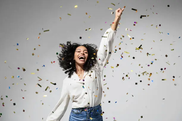 Photo of Beautiful excited woman at celebration party with falling confetti