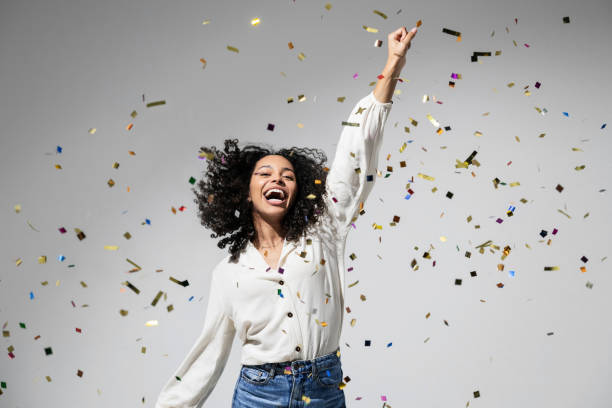 linda mulher animada em festa de comemoração com confete caindo - jump for joy - fotografias e filmes do acervo