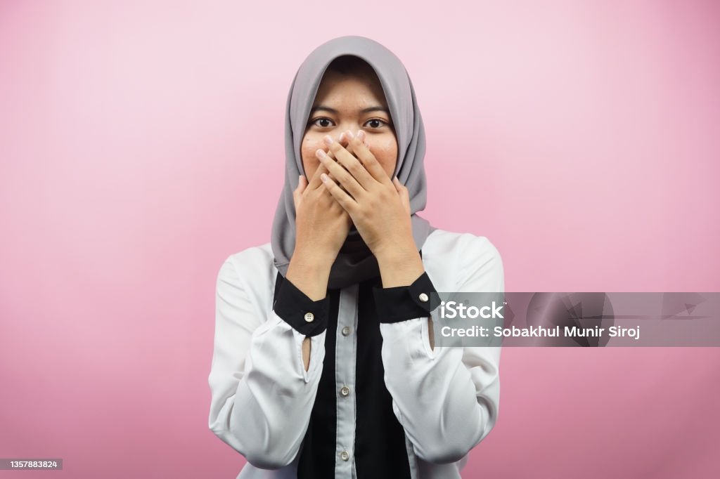 Beautiful young asian muslim woman shocked, surprised, disbelieving, getting shocking information, with hands covering mouth isolated on pink background 20-24 Years Stock Photo