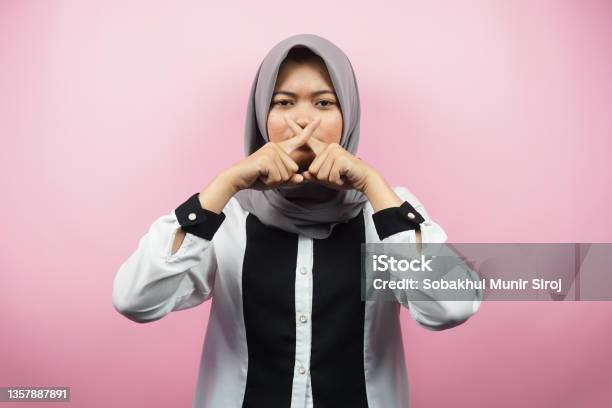 Beautiful Asian Young Muslim Woman With Finger On Mouth Telling To Be Quiet Dont Make Noise Lower Your Voice Dont Talk Isolated On Pink Background Stock Photo - Download Image Now