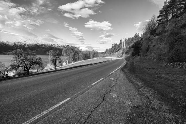 istock road over a pass in norway, between mountains and snow in black and white. 1357889254