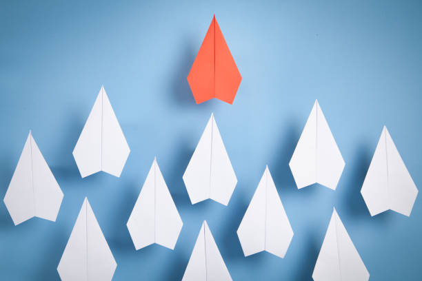 istock Red and white paper airplanes on blue background. Leadership. Teamwork 1357889625