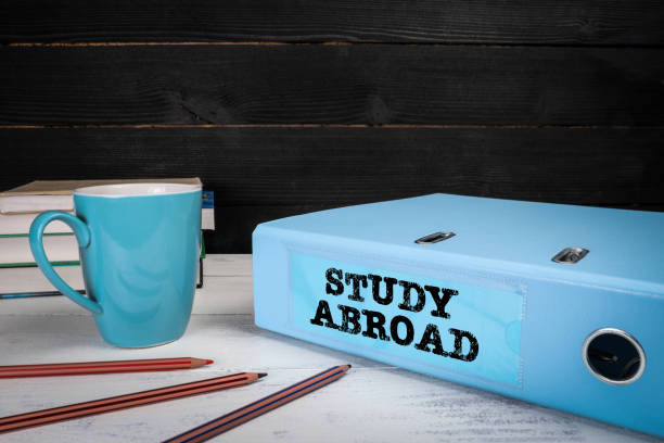 istock Study Abroad. Office or student wooden table with documents and books 1357890758