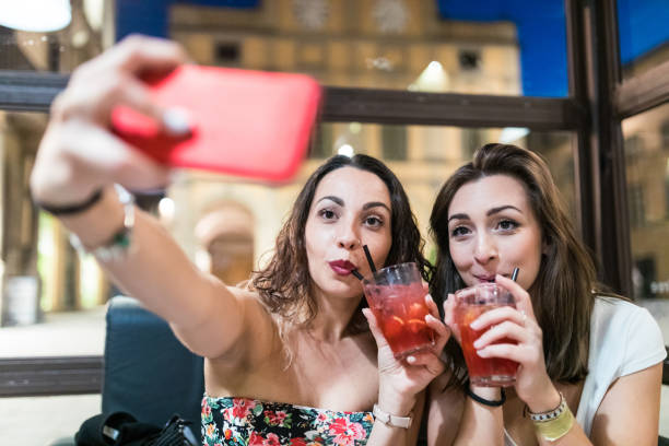 Two happy women taking a selfie while enjoying a drink stock photo