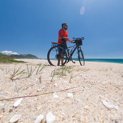 Middle-aged man with a touring bike on Armação beach in Florianópolis in southern Brazil
