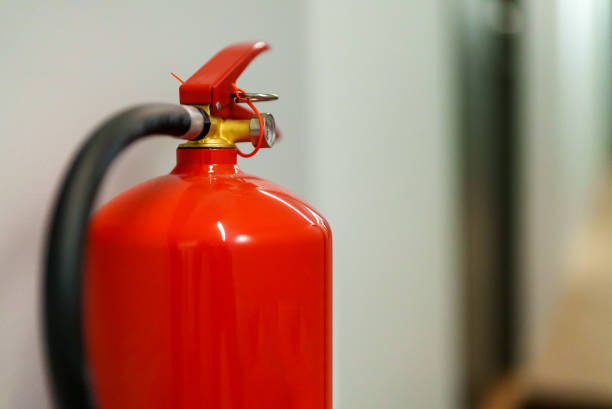 Red fire extinguisher hanging on the wall. stock photo