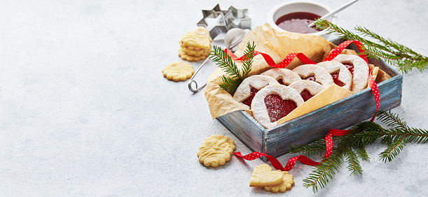 Classic Linzer Christmas Cookies with raspberry or strawberry jam in wooden box on light background. Long wide banner.