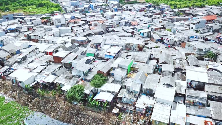 Slum houses on lakeside with an operated excavator