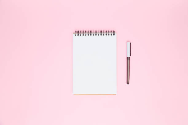 istock White blank open spiral notebook and pen isolated on pastel pink background. Flat lay, copy space. Creative work, business, finance or education concept 1357899382