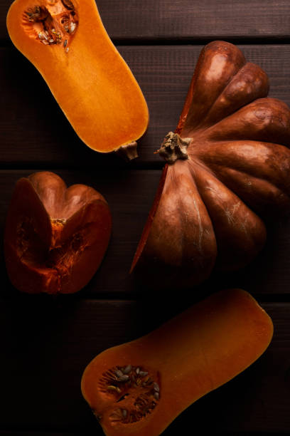 istock Two different sliced ripe orange pumpkins closeup wooden background 1357899526