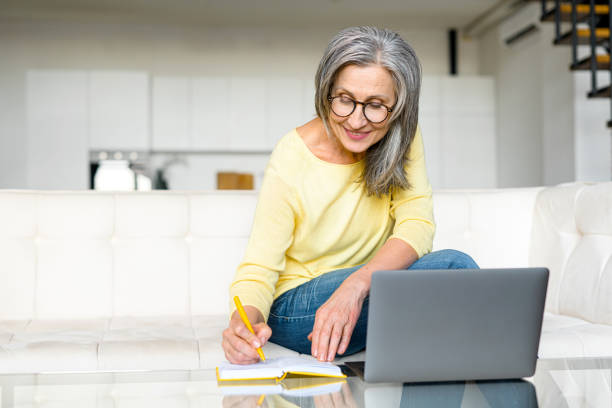 istock Focused retired woman is learning online, using a laptop for watching online classes 1357899566