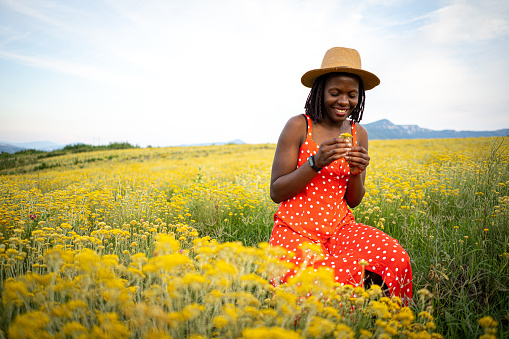 A woman with a hat enjoys a field of flowers