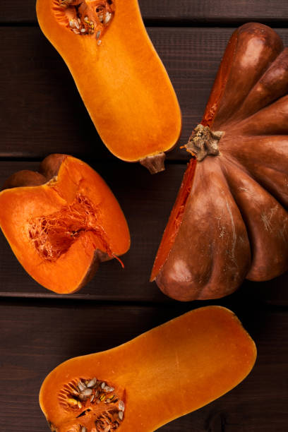 istock Two different sliced ripe orange pumpkins closeup wooden background 1357899651