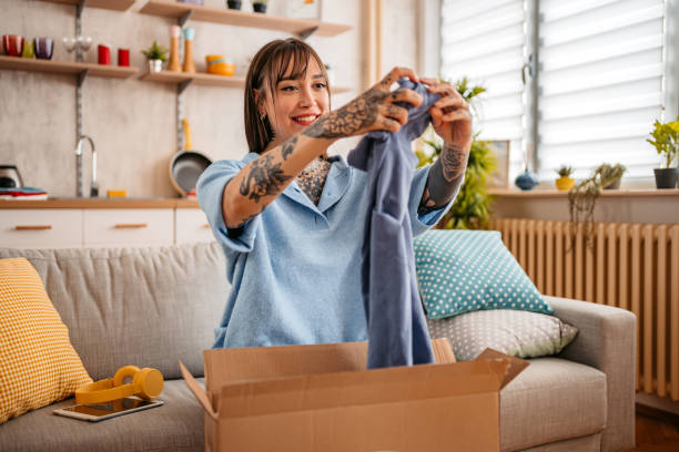 pacchetto di disimballaggio donna con nuova t-shirt a casa - unboxing foto e immagini stock