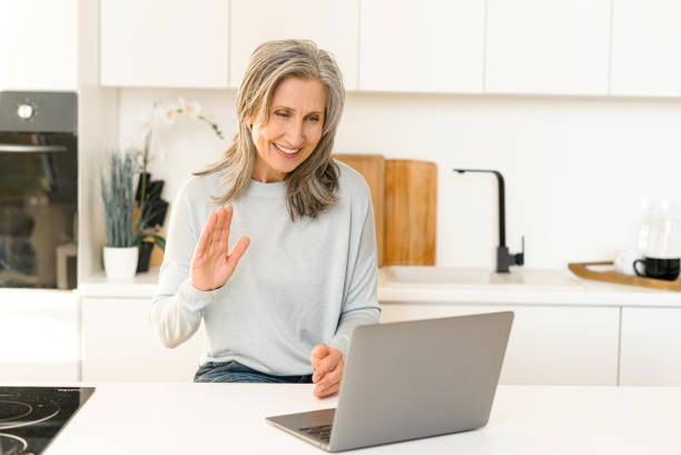 istock Good-looking senior mature woman is using laptop for video connection 1357900567