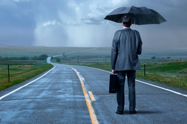 istock Man Standing With Umbrella On Long Cold And Wet Road 1357900897