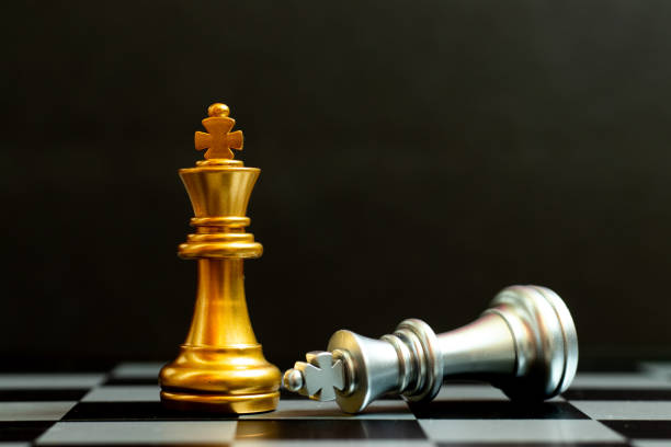 istock Gold king chess piece win over lying down silver king on black background 1357902259