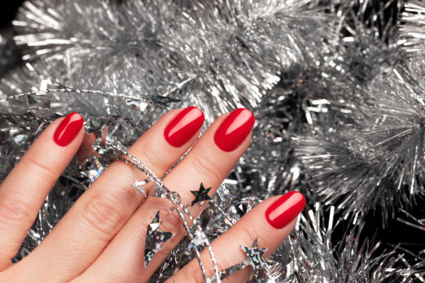 istock Hand with red nails with Christmas tinsel 1357903512