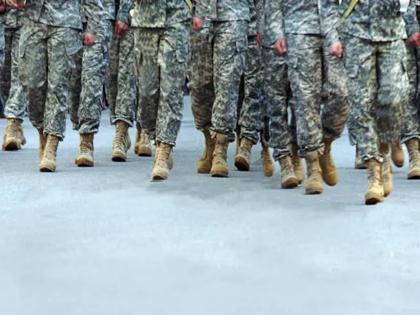 Feet wearing boots of Soldiers marching on pavement