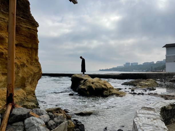istock Man standing on a rock in sea water 1357907253