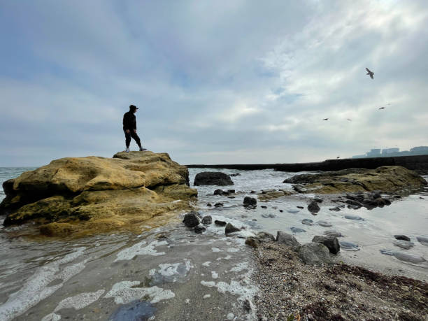 istock Man standing on a rock in sea water 1357907254