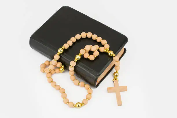 Closeup of wooden Christian cross on bible and prayer beads on black.Church utensils.