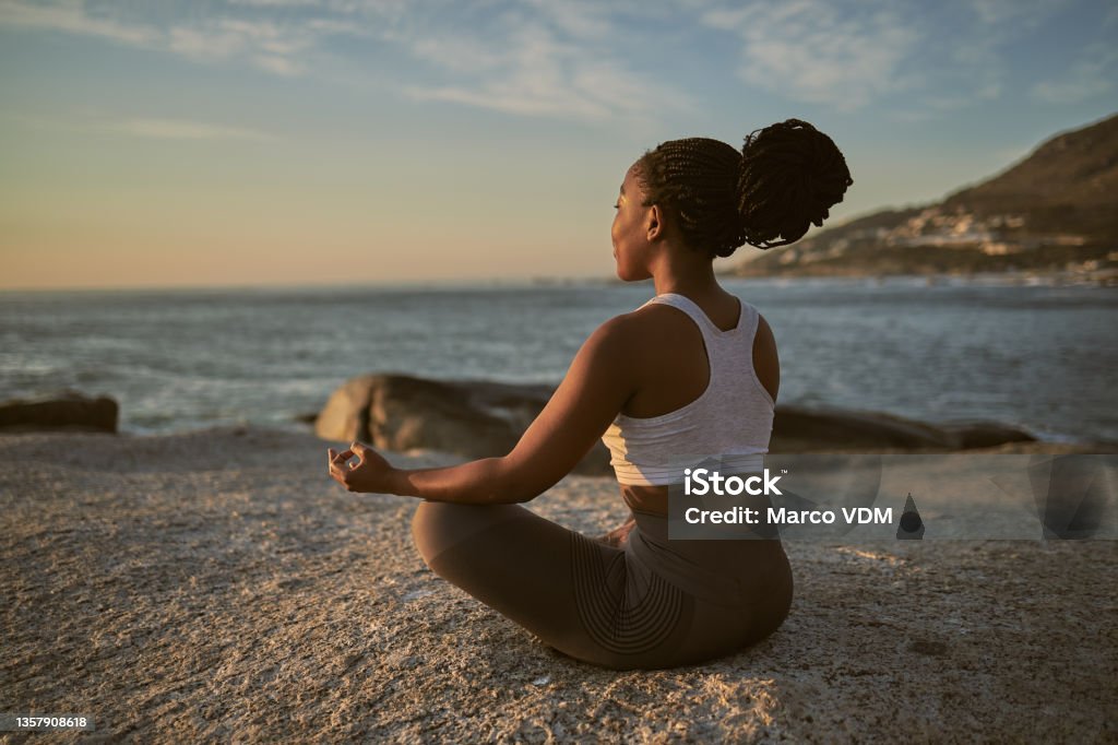 Full length shot of an attractive young woman practising yoga on the beach In search of inner peace Meditating Stock Photo