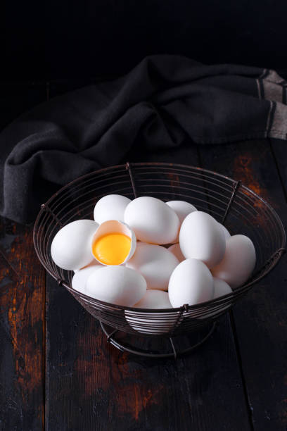 istock Basket of colorful fresh eggs on wooden table rustic background. 1357910411