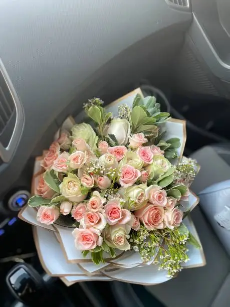 A pink and white roses bouquet in the car