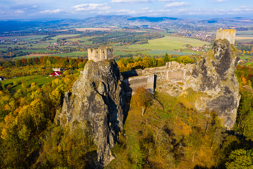 Aerial view of two towers of ruined abandoned Trosky Castle on tops  of stone rocks domineering over Czech nature reserve of Bohemian Paradise in autumn