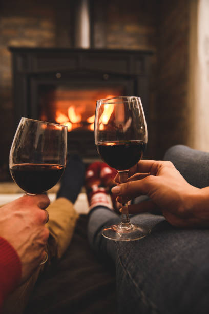 istock Romantic couple cheering with red wine by the cozy fireplace 1357911635