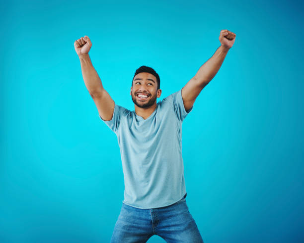 istock Shot of a handsome young man looking cheerful while posing against a blue background 1357914682