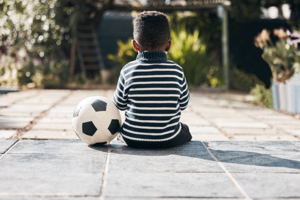 tiro de um menino adorável sentado do lado de fora com sua bola - unrecognizable person one person child childhood - fotografias e filmes do acervo