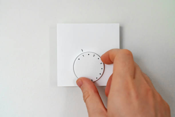 istock Man turning on heating thermostat to get warm. 1357916128