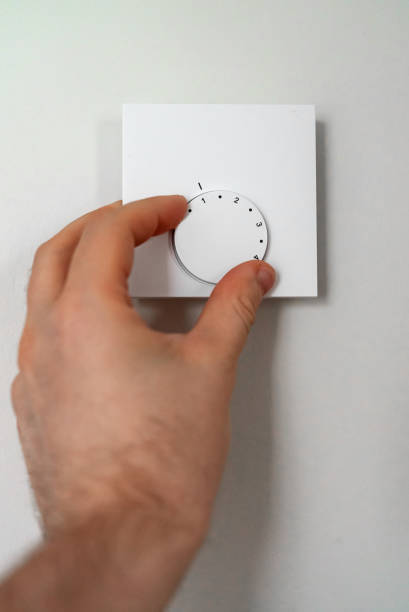 istock Man turning on heating thermostat to get warm. 1357916132