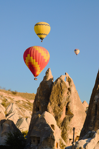 Scenic morning landscape view of flying hot air balloons over amazing cave houses in shaped sandstone rocks near Goreme. Popular travel destination in Turkey.