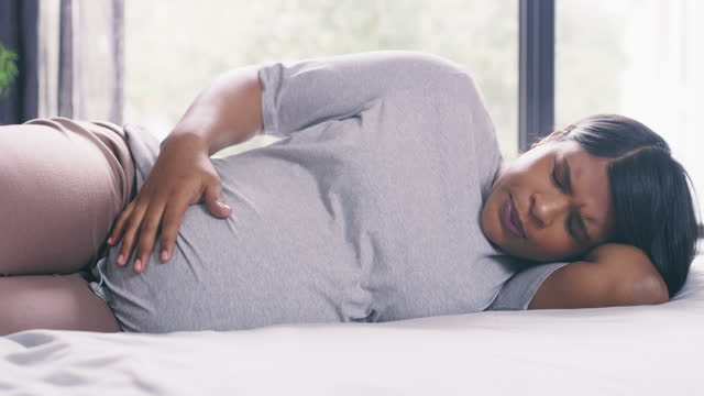 4k video footage of a young pregnant woman experiencing contractions at home