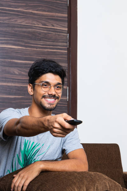 istock young indian boy pointing the television remote and smiling 1357918085
