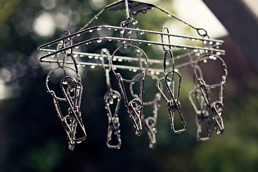 Stainless steel clothes pegs with water droplets. Wet season rainy day conceptual photo. selective focus