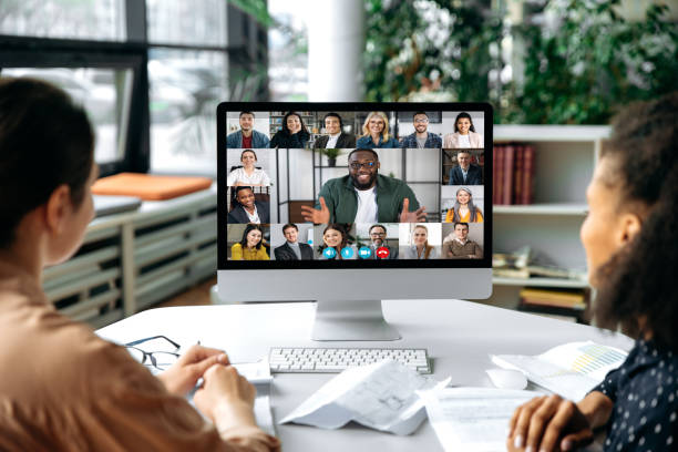 istock Virtual communication, video call. View over the shoulders of two women to a computer screen with successful multiracial business team gathered in a video conference to discuss working issues,strategy 1357921508