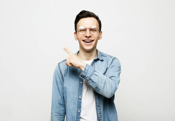 istock Young handsome man smiling cheerfully, feeling happy and pointing to the side and upwards 1357924633