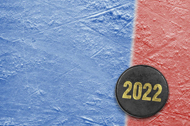 istock Hockey puck on blue ice with red stripe 1357925902